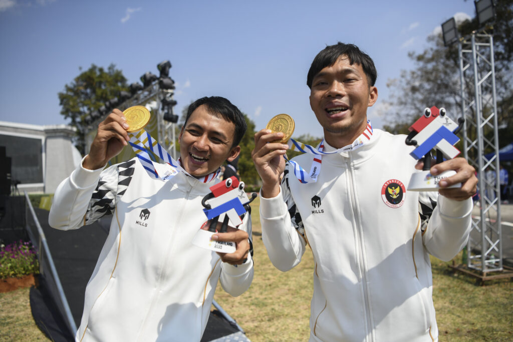 Atlet balap sepeda Indonesia Nurfendi (kanan) dan pilotnya Mufti Fadilah (kiri) menunjukkan medali emas yang mereka terima setelah berhasil mengalahkan lawan-lawannya dalam kategori Road Cycling Men's B - Time Trial di ASEAN Para Games 2025 di Suranaree Un