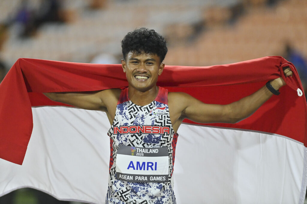 Atlet NPC Indonesia Rezza Surya Amri berpose dengan Bendera Merah Putih setelah berhasil memenangkan pertandingan nomor lompat jauh T46, T47 ASEAN Para Games 2025 di 80th Birthday Anniversary Commemorative Stadium di Nakhon Rachatsima, Thailand, Sabtu (24/